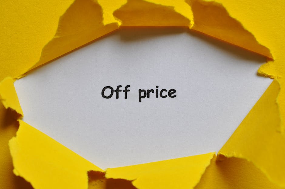 A torn yellow paper reveals a white inner surface with the handwritten phrase 'Off price' in black ink. The torn edges of the paper are irregular, showcasing a contrast between the bright yellow exterior and the clean white interior, suggesting a packaging or promotional context. The background and surrounding area are out of view, focusing solely on the torn paper and the message inside. This image subtly relates to packing or discount offers associated with house removals or moving services, as provided by Putney Man and Van, specialists in furniture transport and home relocation in SW15.